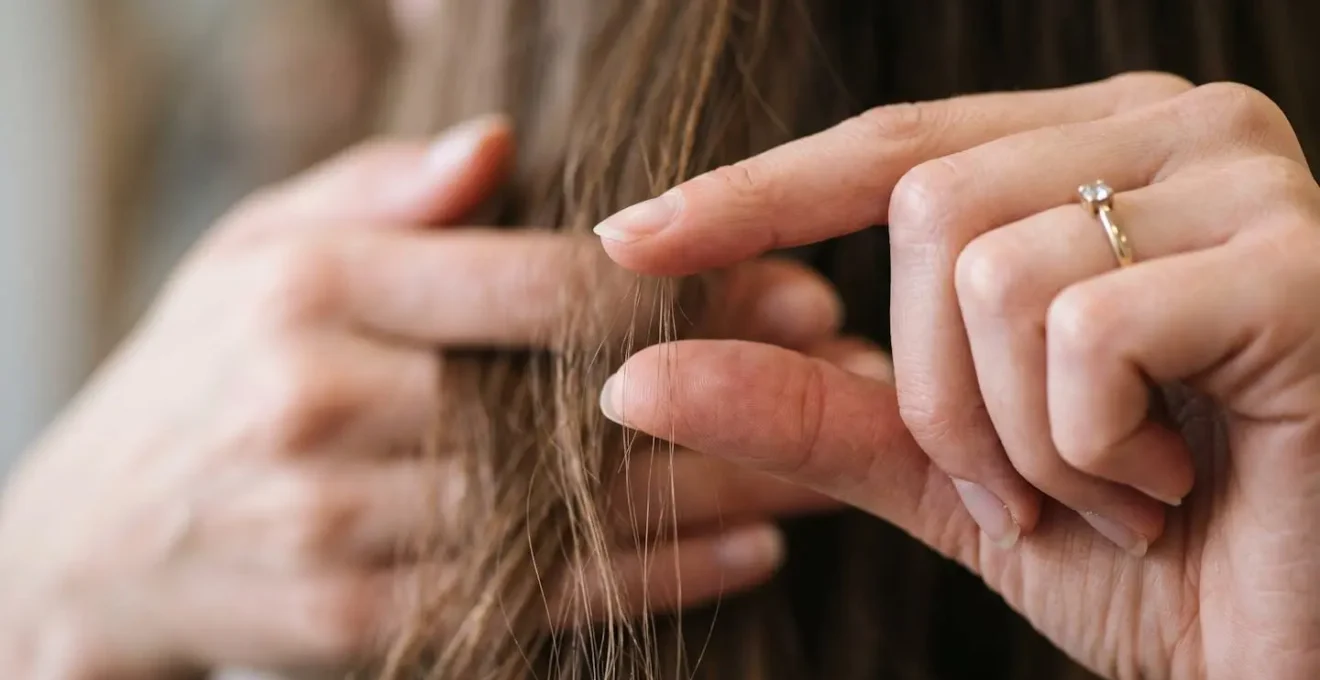 Mains montrant geste précis de mesure entre doigts pour indiquer longueur coupe cheveux souhaitée