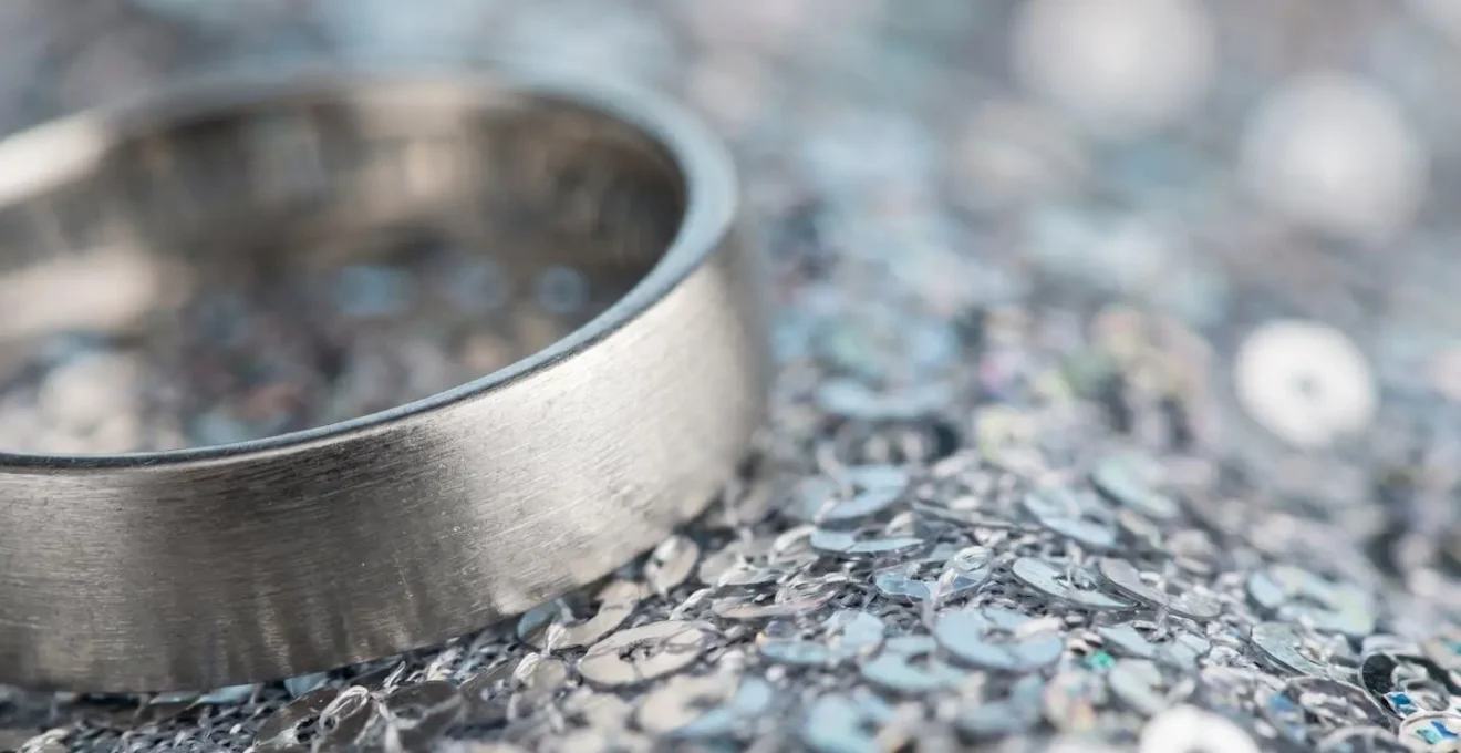 Gros plan sur des bijoux minimalistes en métal mat contrastant avec une texture brillante de sequins