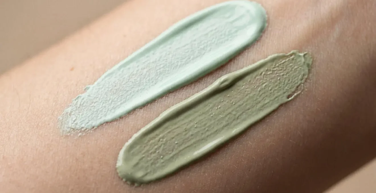 Gros plan sur des textures crémeuses de correcteurs de teint aux nuances vertes subtiles