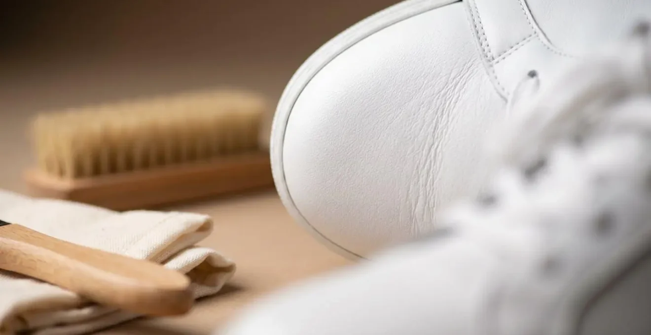 Gros plan sur des produits d'entretien pour sneakers blanches disposés sur un bureau